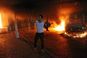 An armed man waves his rifle as buildings and cars are engulfed in flames after being set on fire inside the US consulate compound in Benghazi late on September 11, 2012. An armed mob protesting over a film they said offended Islam, attacked the US consulate in Benghazi and set fire to the building, killing one American, witnesses and officials said. AFP PHOTO (Photo credit should read STR/AFP/GettyImages)