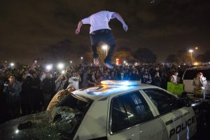 An anti-Trump protester jumps on top of a police vehicle caving in the roof as protesters fill the streets in front of the Orange County Fair & Event Center along Fair Drive after the Trump rally let out in Costa Mesa, California on Thursday, April 28, 2016. (Jose Lopez)